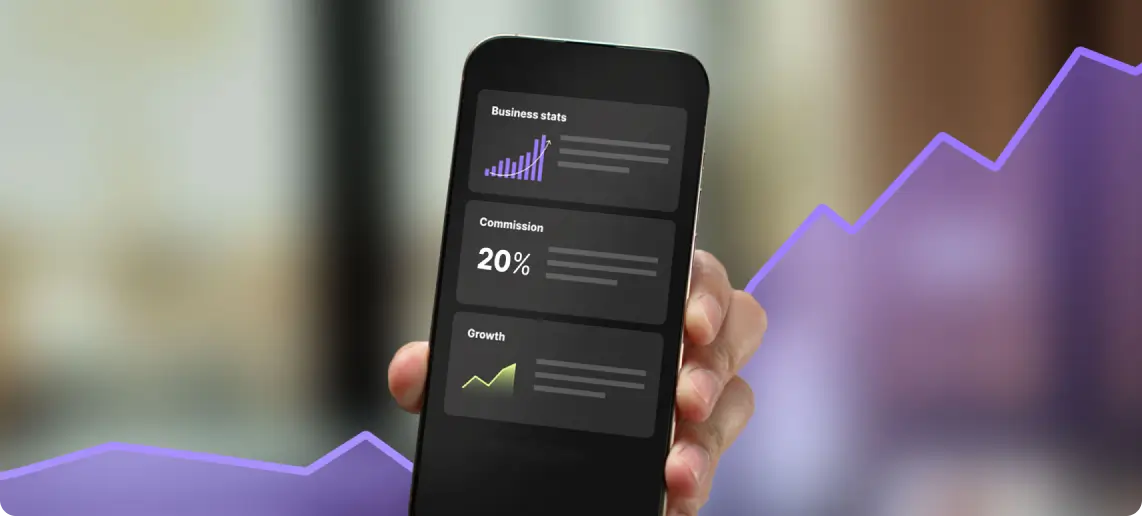 Hand holding a smartphone displaying business stats with charts and a 20% commission figure.